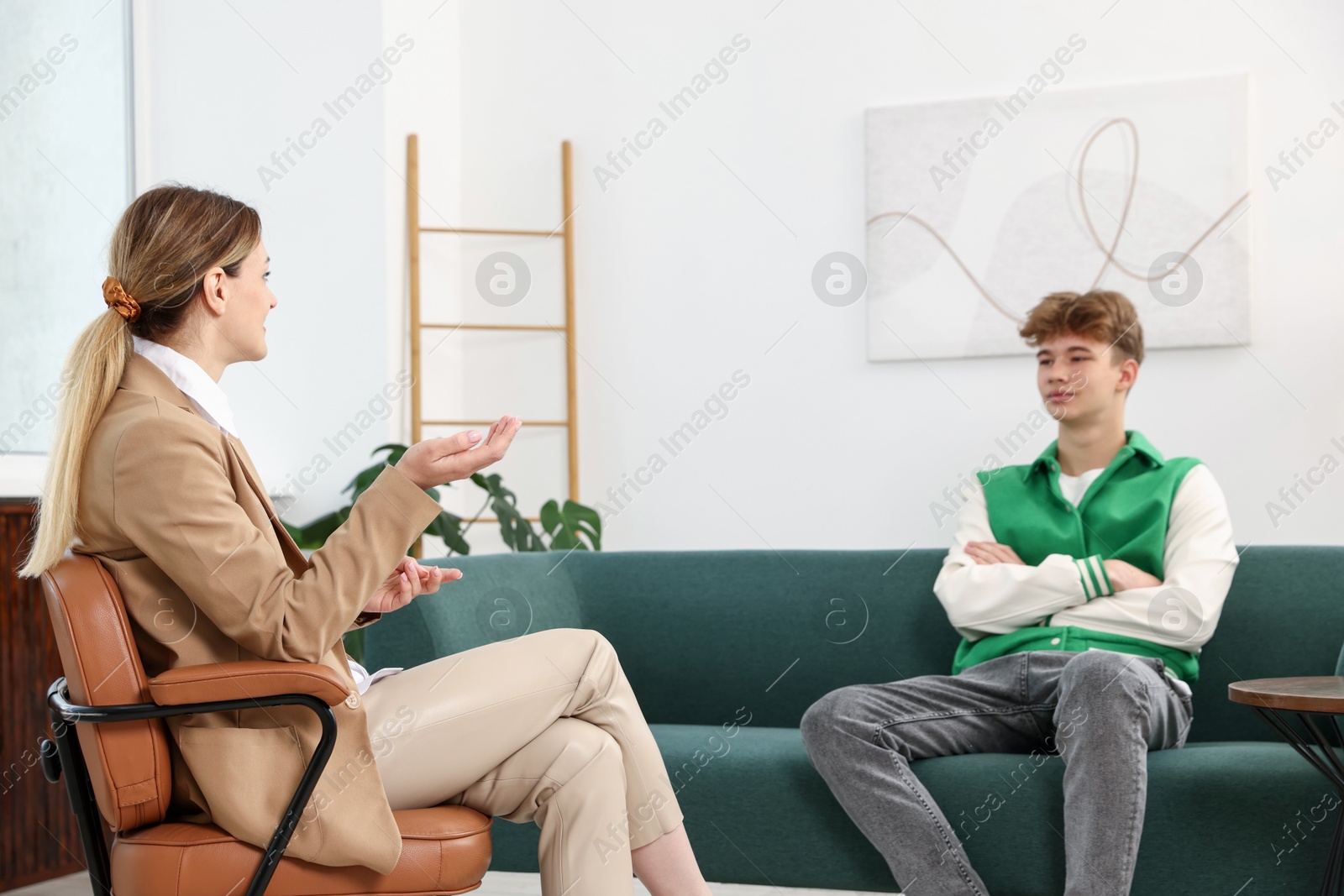 Photo of Professional psychologist working with teenage boy in office