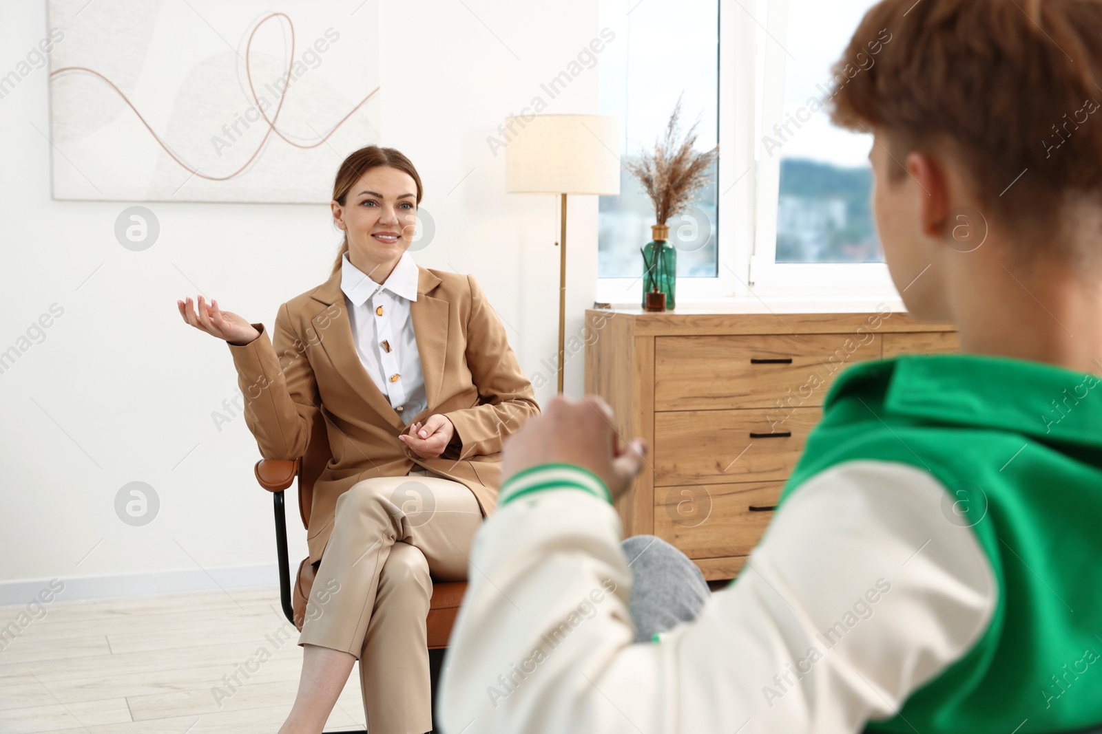 Photo of Professional psychologist working with teenage boy in office