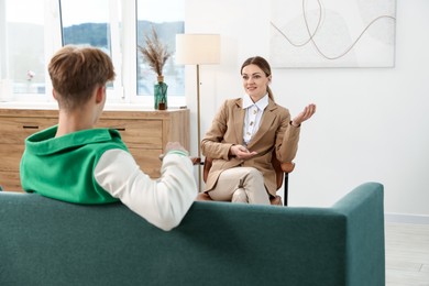Photo of Professional psychologist working with teenage boy in office