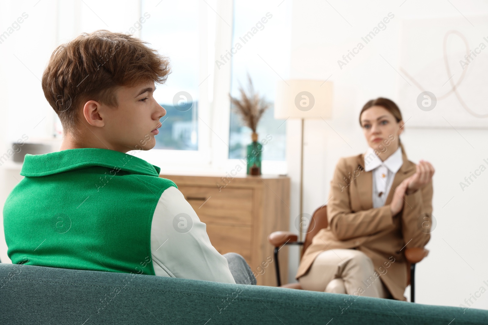Photo of Professional psychologist working with teenage boy in office, selective focus