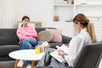 Photo of Professional psychologist working with teenage girl in office, selective focus