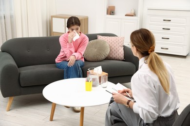 Photo of Professional psychologist working with teenage girl in office