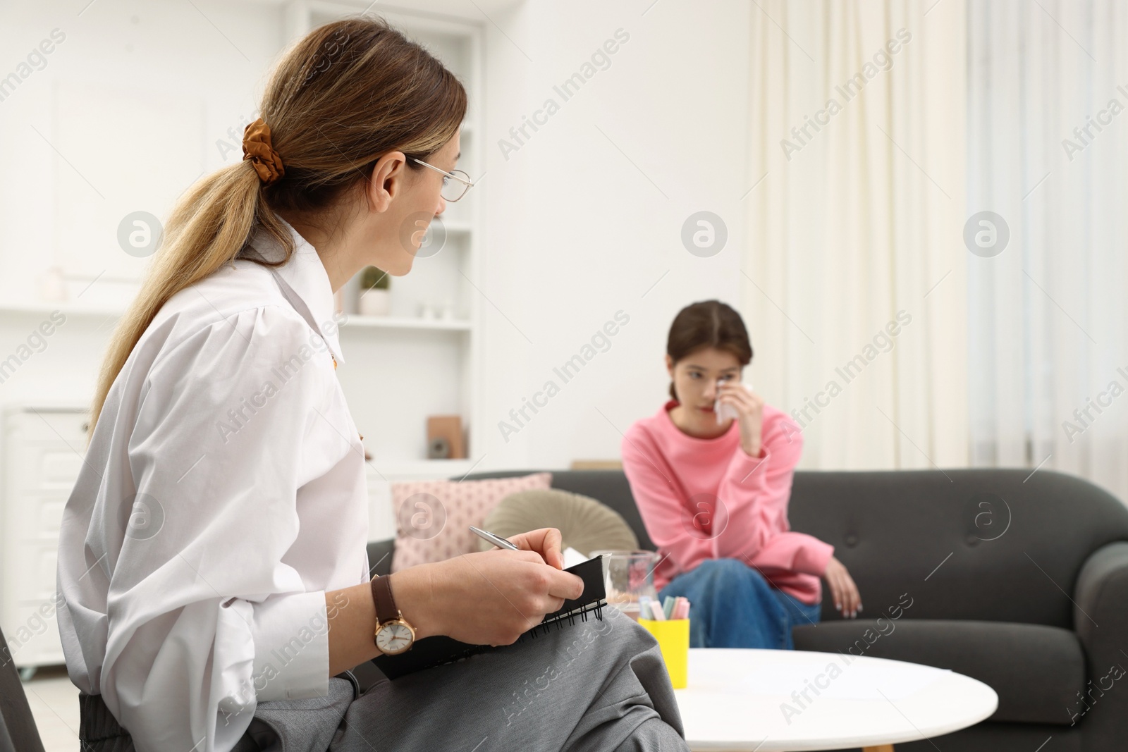 Photo of Professional psychologist working with teenage girl in office, selective focus