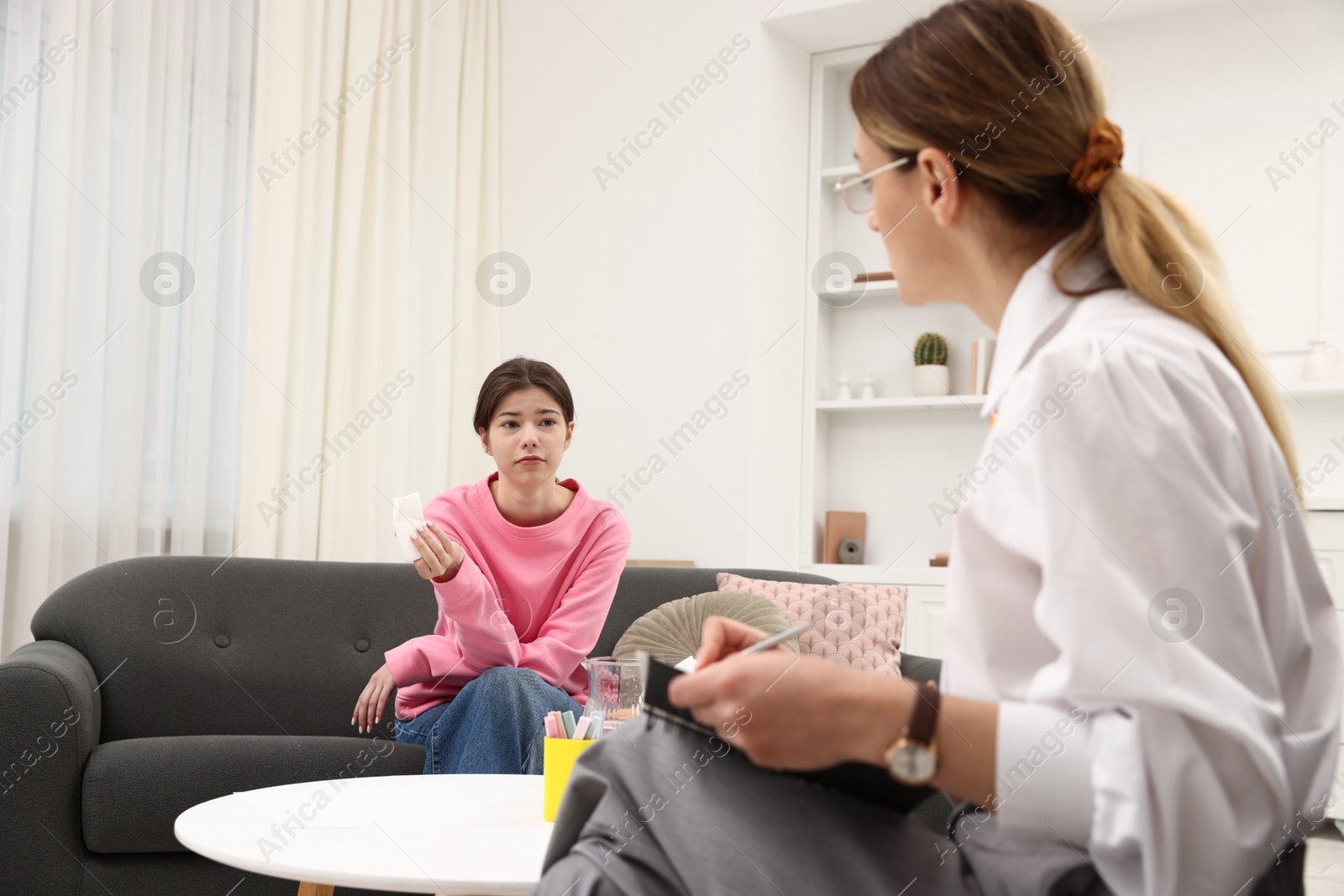 Photo of Professional psychologist working with teenage girl in office
