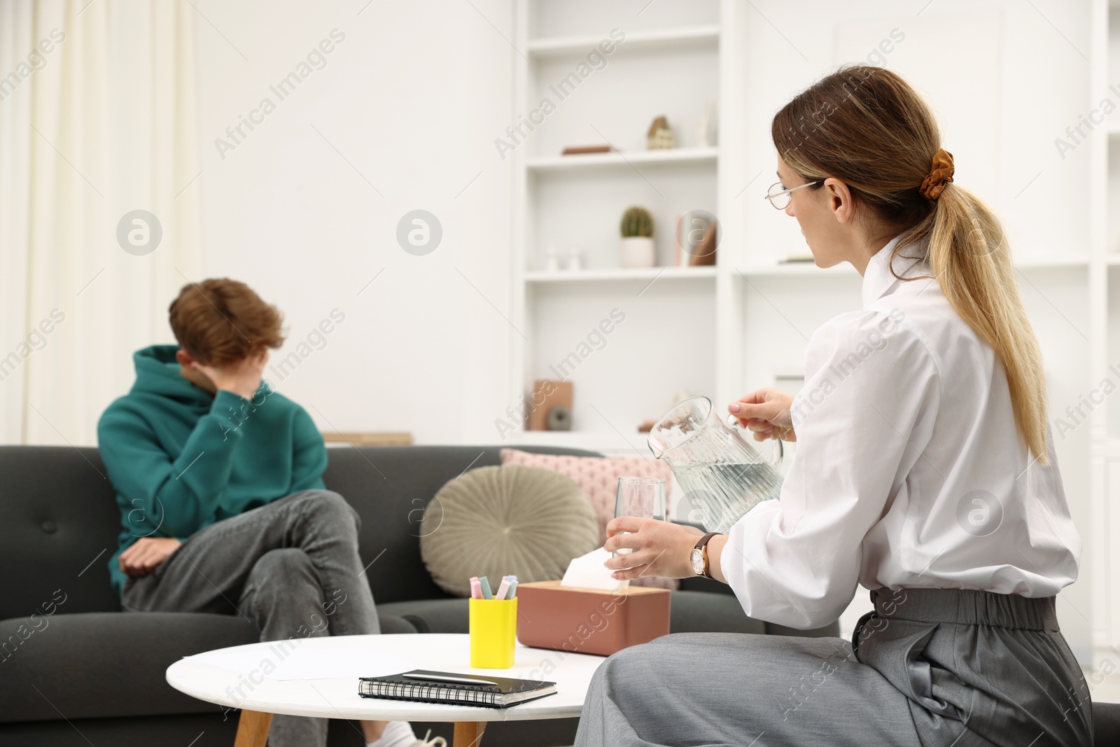 Photo of Professional psychologist working with teenage boy in office, selective focus