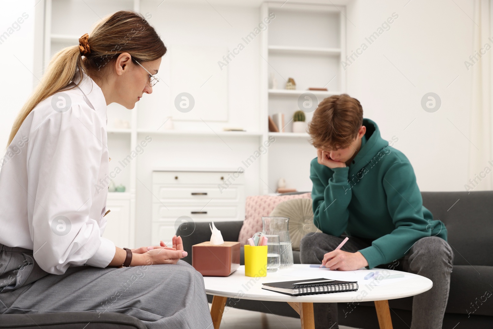 Photo of Professional psychologist working with teenage boy in office