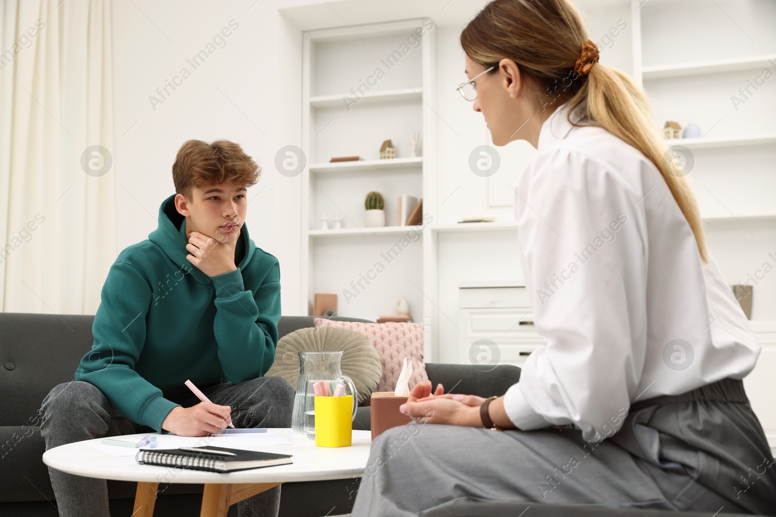 Photo of Professional psychologist working with teenage boy in office