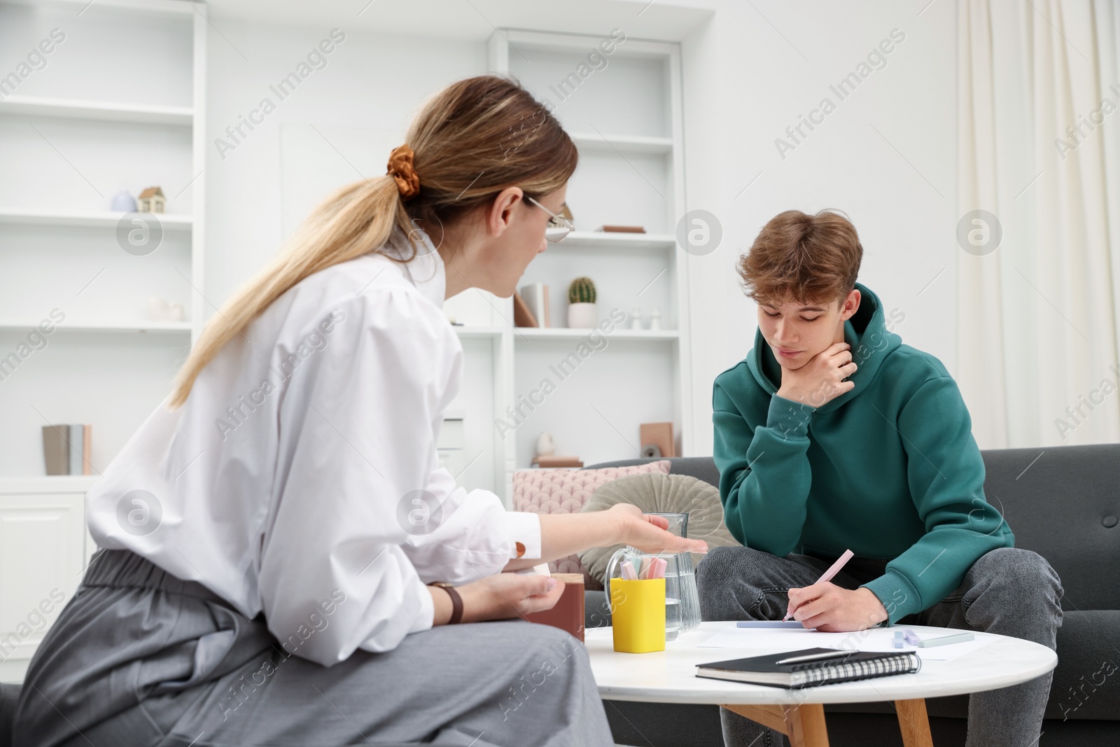 Photo of Professional psychologist working with teenage boy in office
