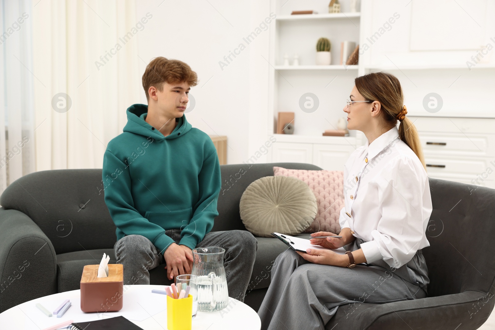 Photo of Professional psychologist working with teenage boy in office