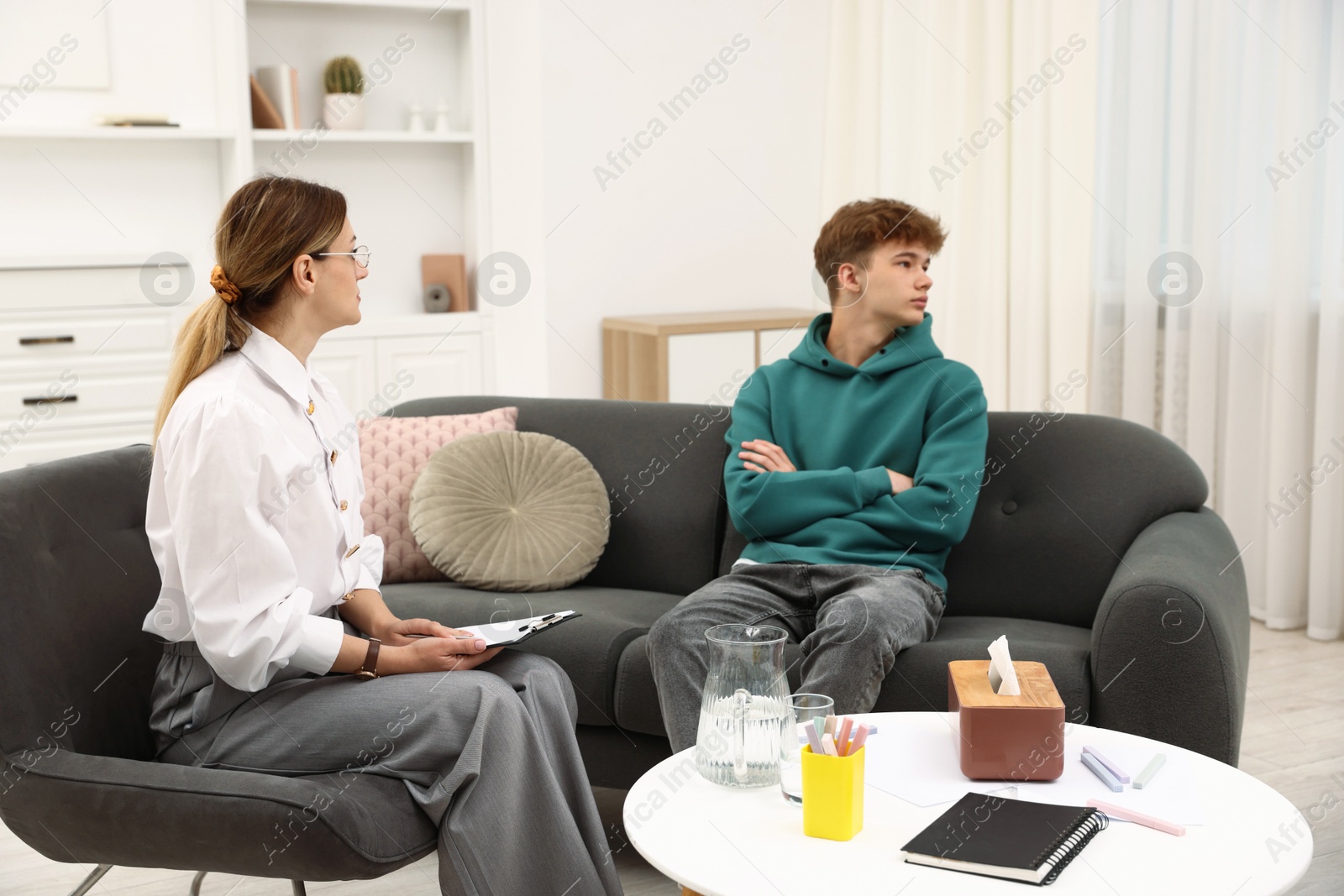 Photo of Professional psychologist working with teenage boy in office