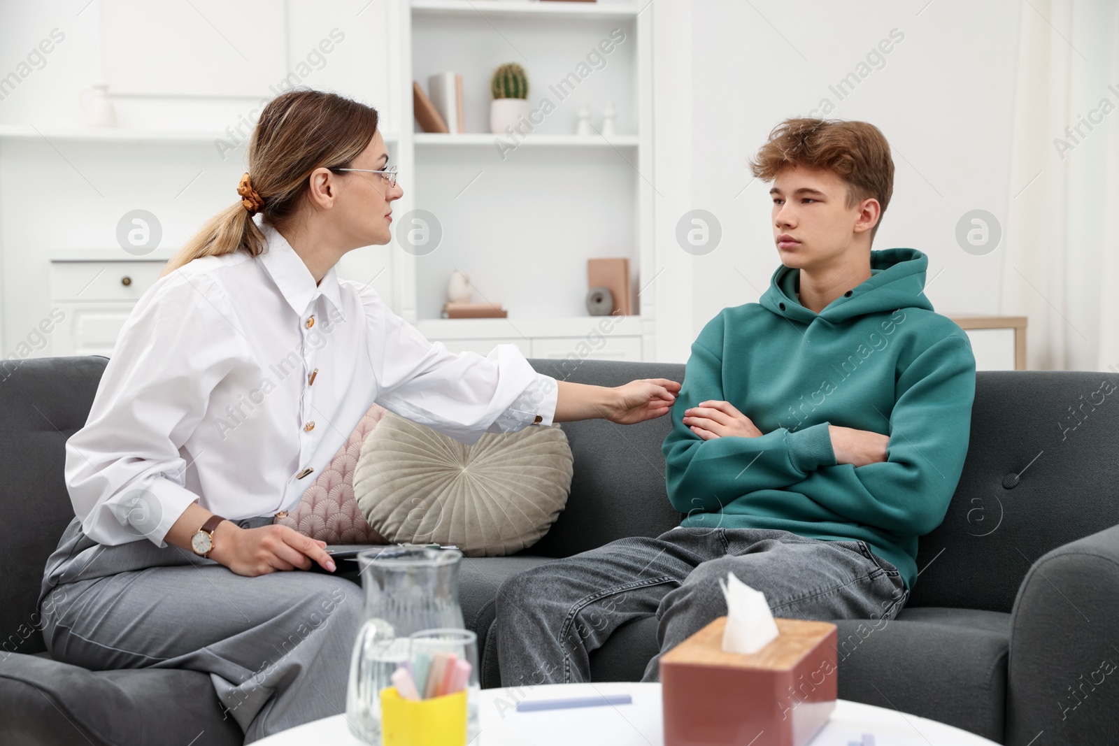 Photo of Professional psychologist working with teenage boy in office