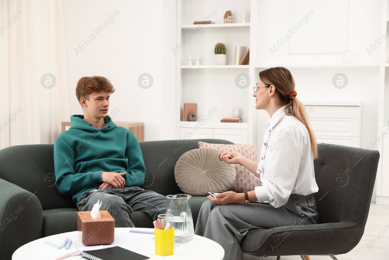 Photo of Professional psychologist working with teenage boy in office