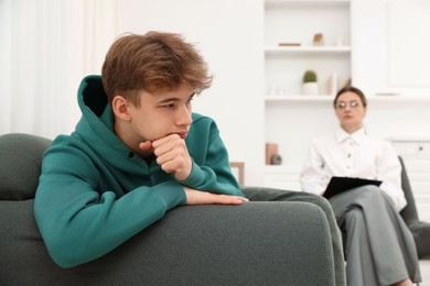 Photo of Professional psychologist working with teenage boy in office, selective focus