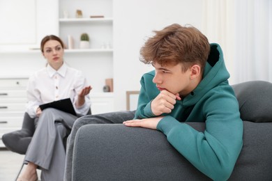 Photo of Professional psychologist working with teenage boy in office, selective focus