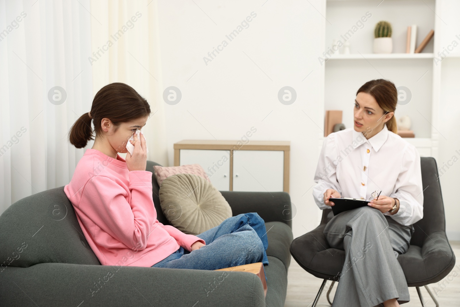 Photo of Professional psychologist working with teenage girl in office