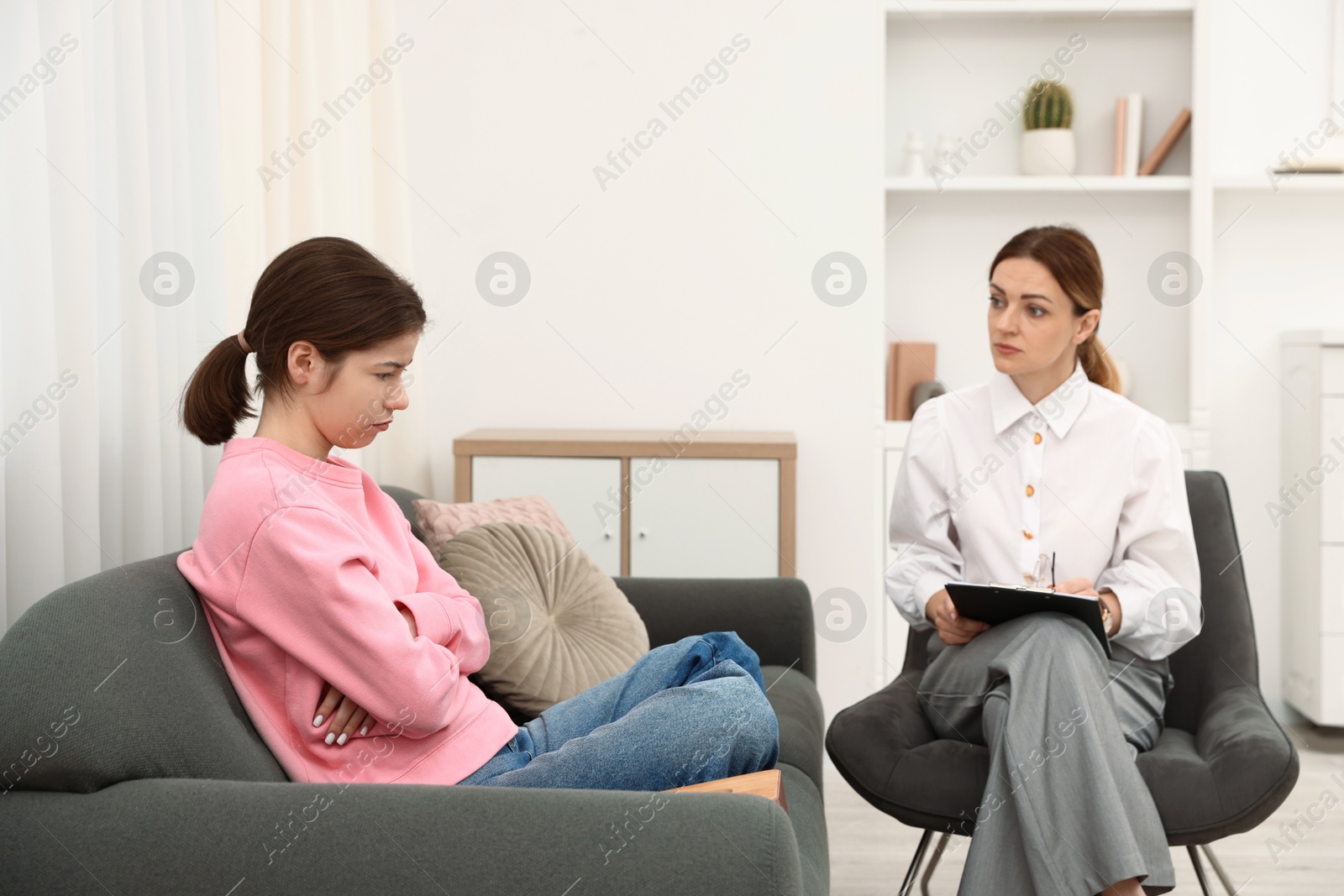 Photo of Professional psychologist working with teenage girl in office