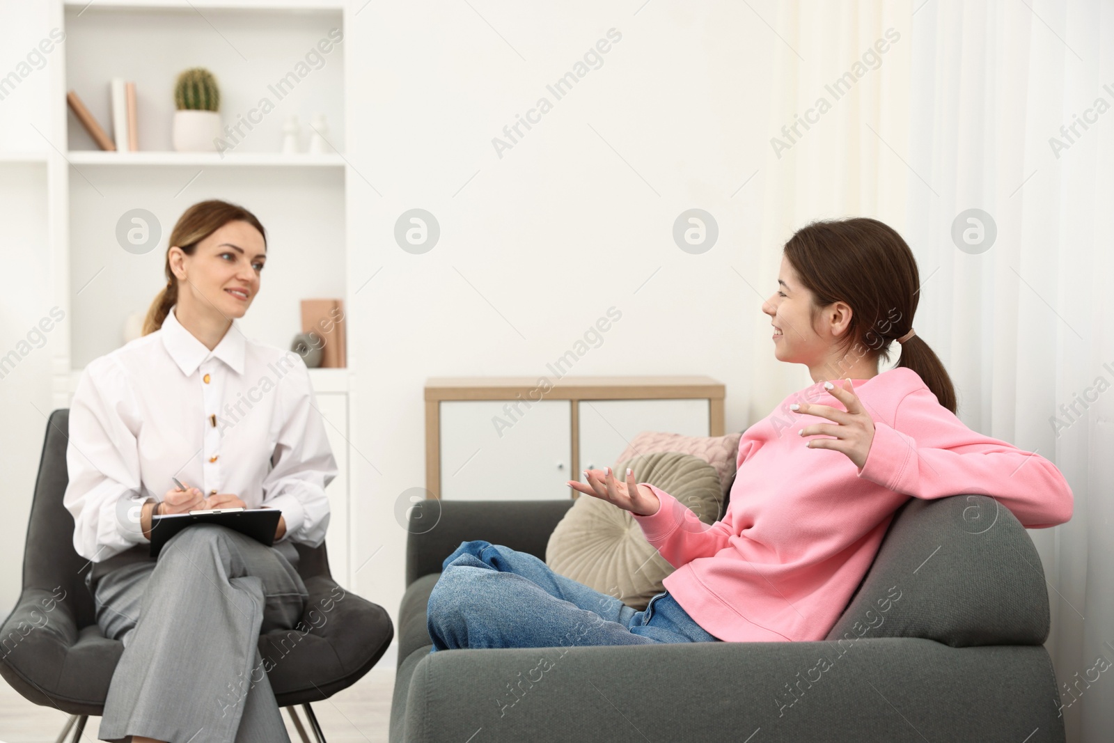 Photo of Professional psychologist working with teenage girl in office
