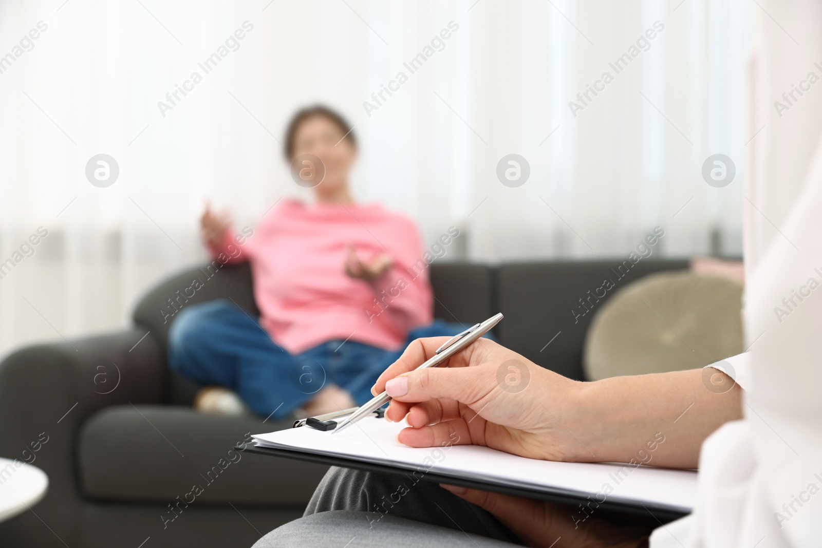 Photo of Professional psychologist working with teenage girl and writing in clipboard in office, selective focus