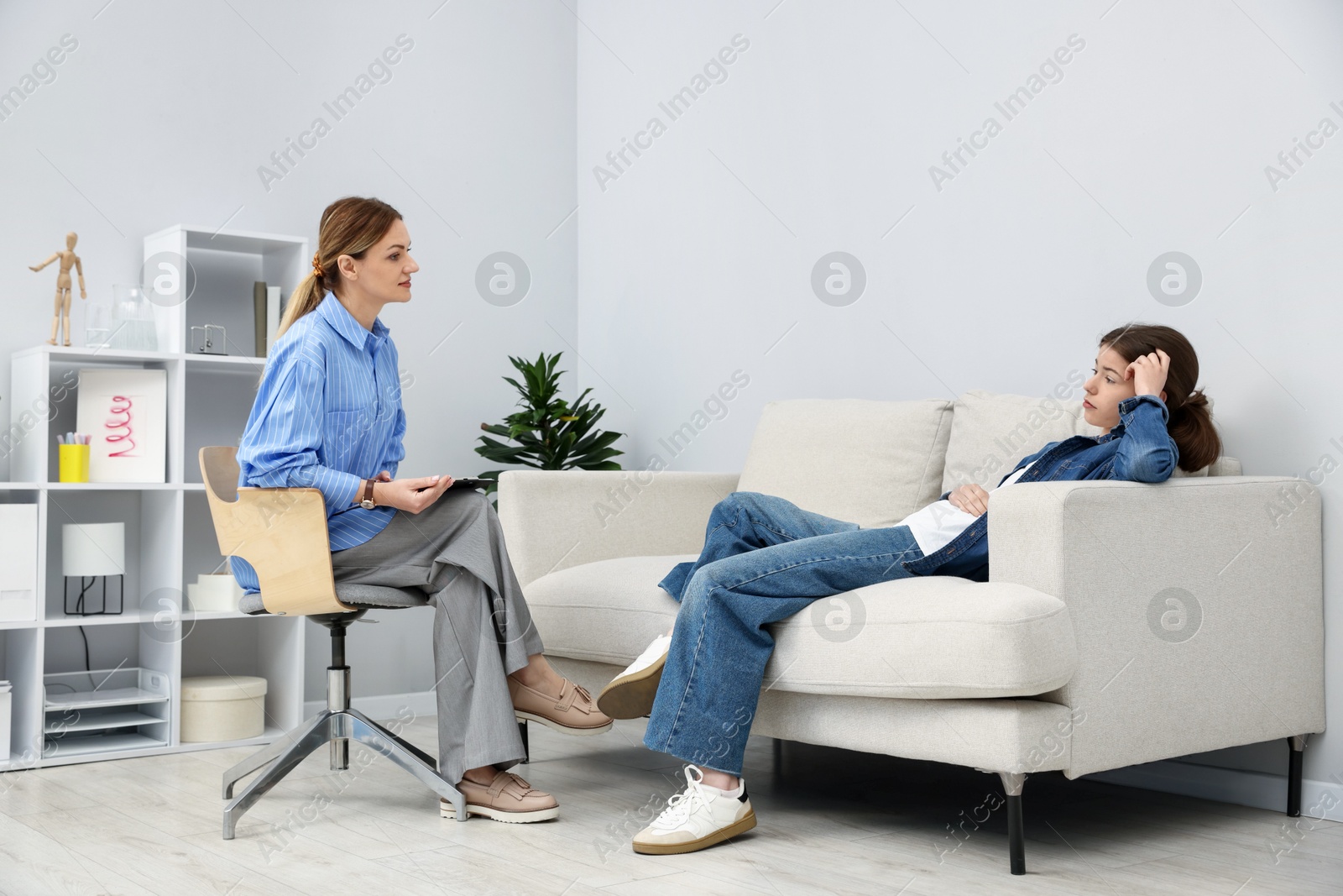 Photo of Professional psychologist working with teenage girl in office
