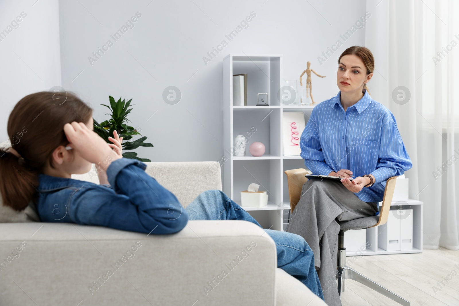 Photo of Professional psychologist working with teenage girl in office