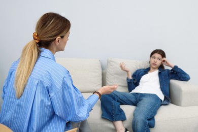 Photo of Professional psychologist working with teenage girl in office, selective focus