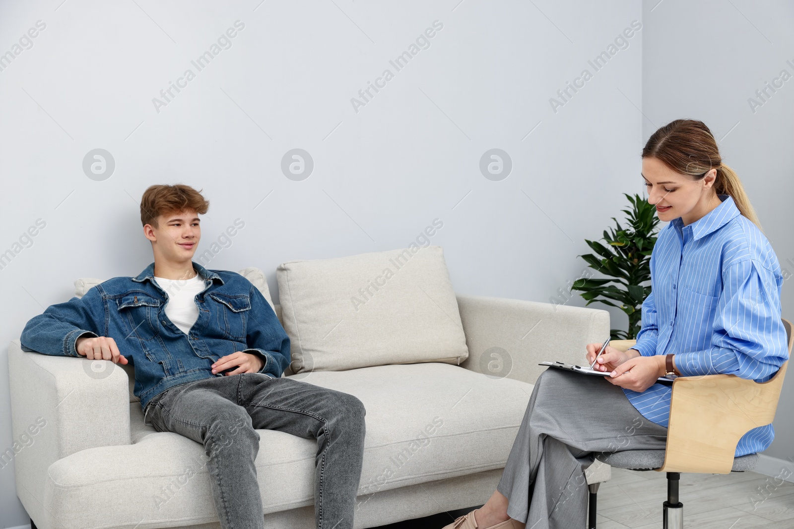 Photo of Professional psychologist working with teenage boy in office
