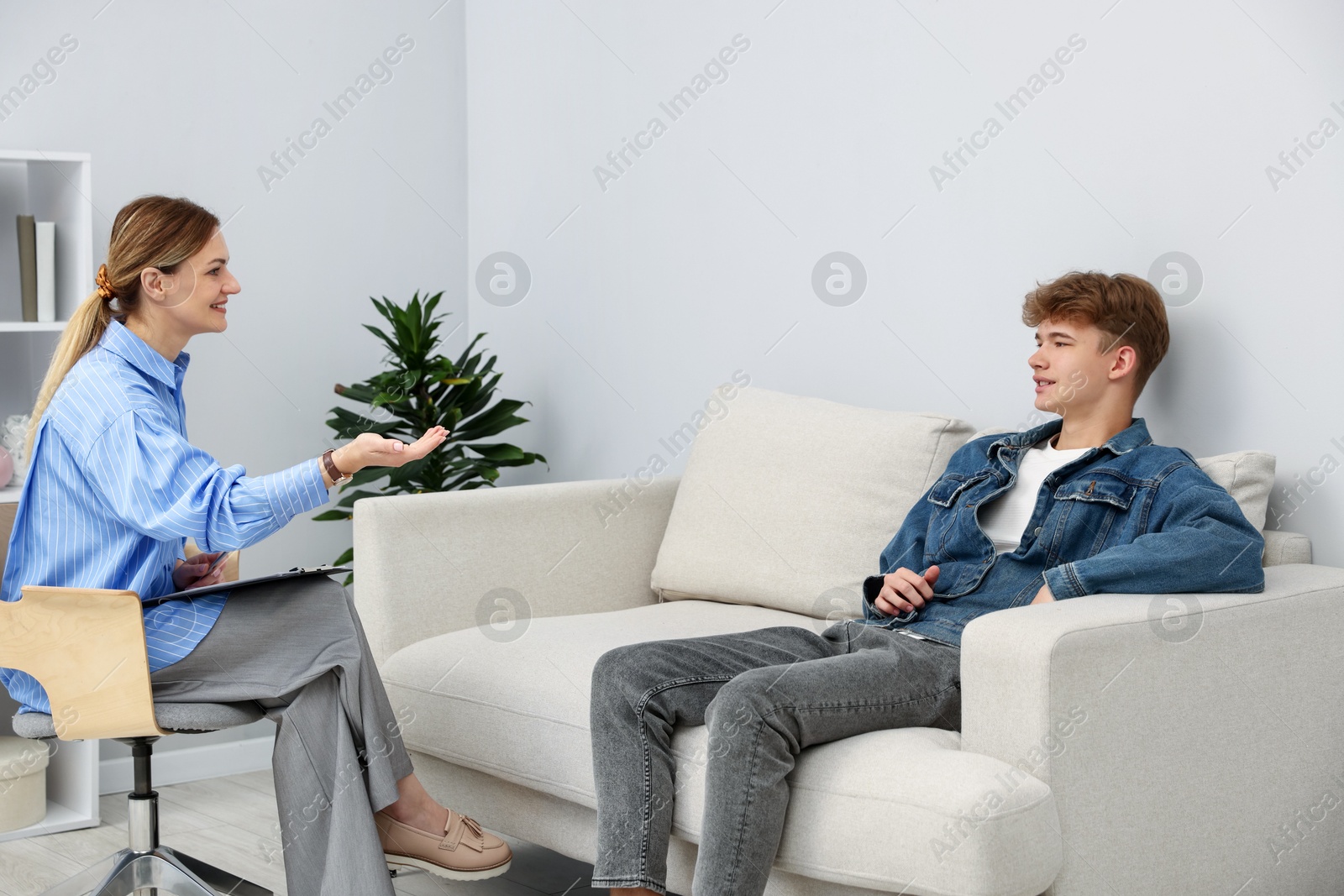 Photo of Professional psychologist working with teenage boy in office