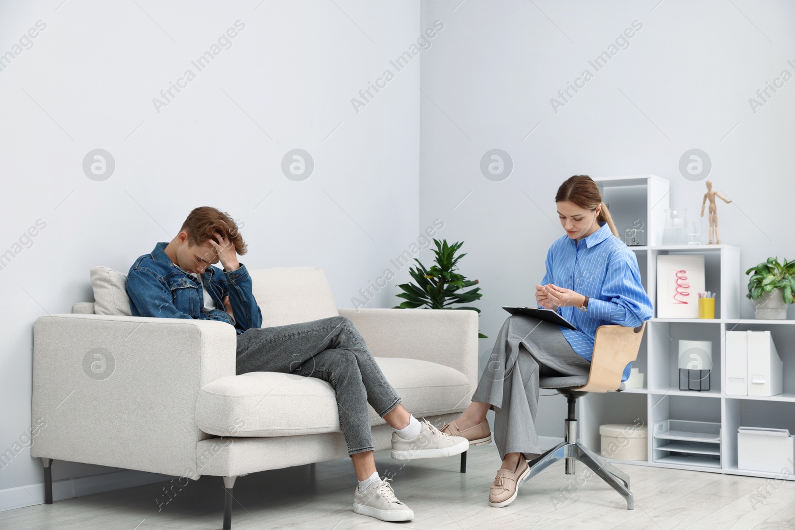Photo of Professional psychologist working with teenage boy in office