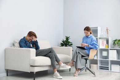 Photo of Professional psychologist working with teenage boy in office