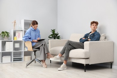 Photo of Professional psychologist working with teenage boy in office