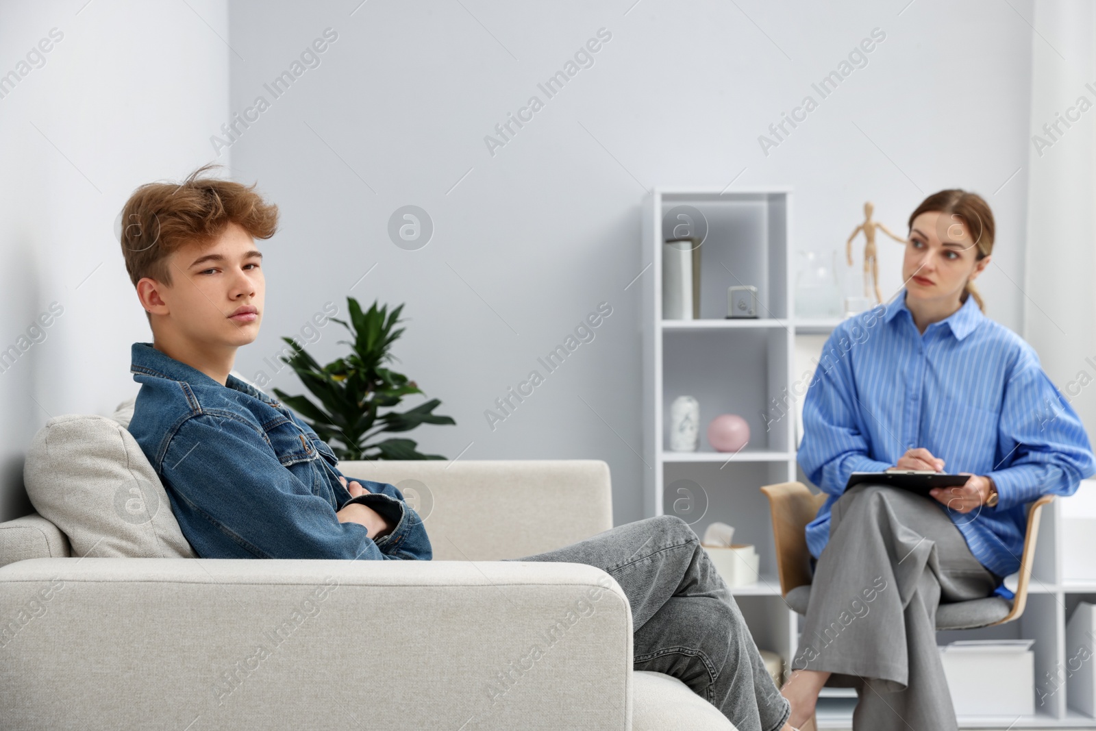 Photo of Professional psychologist working with teenage boy in office