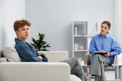Photo of Professional psychologist working with teenage boy in office
