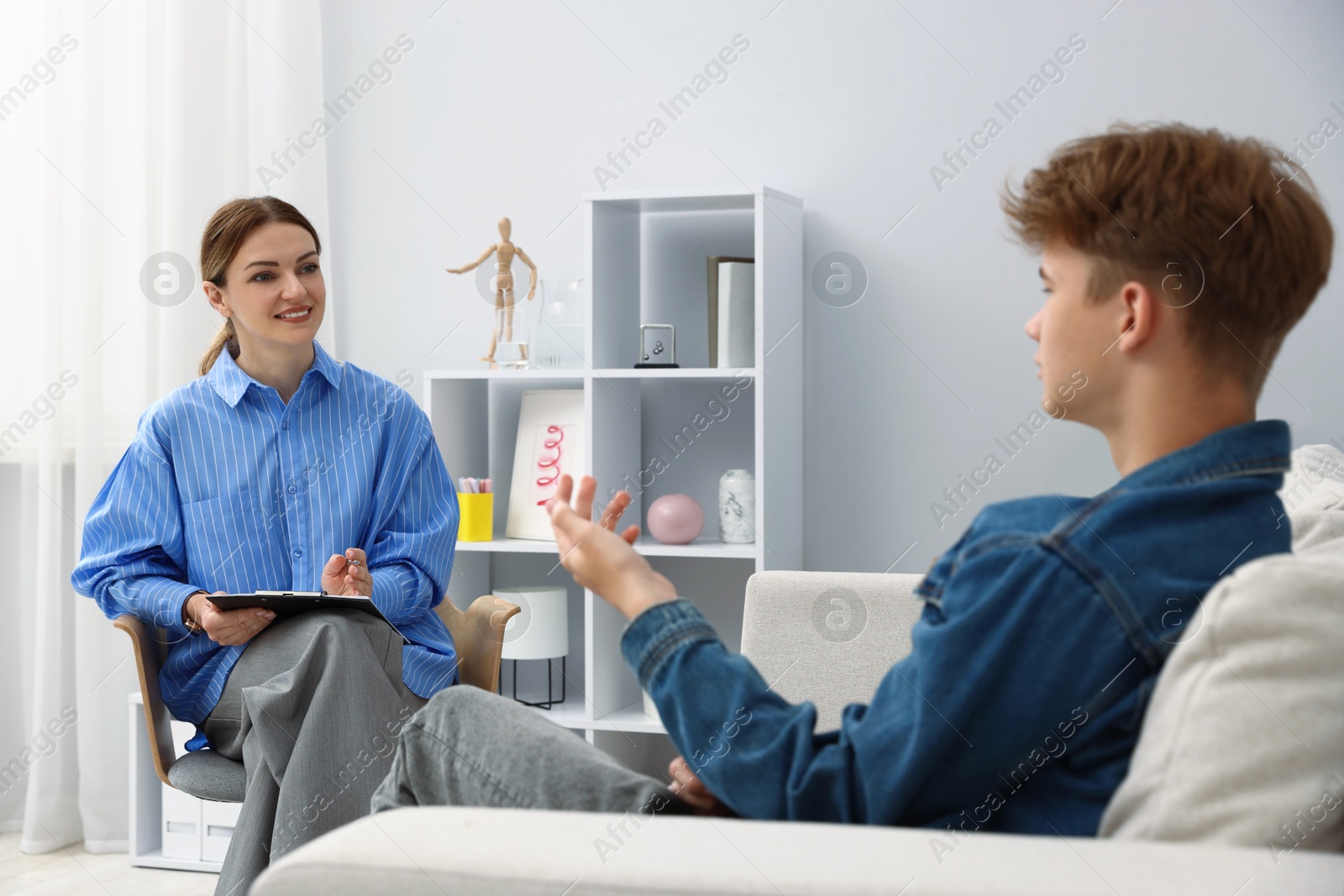 Photo of Professional psychologist working with teenage boy in office