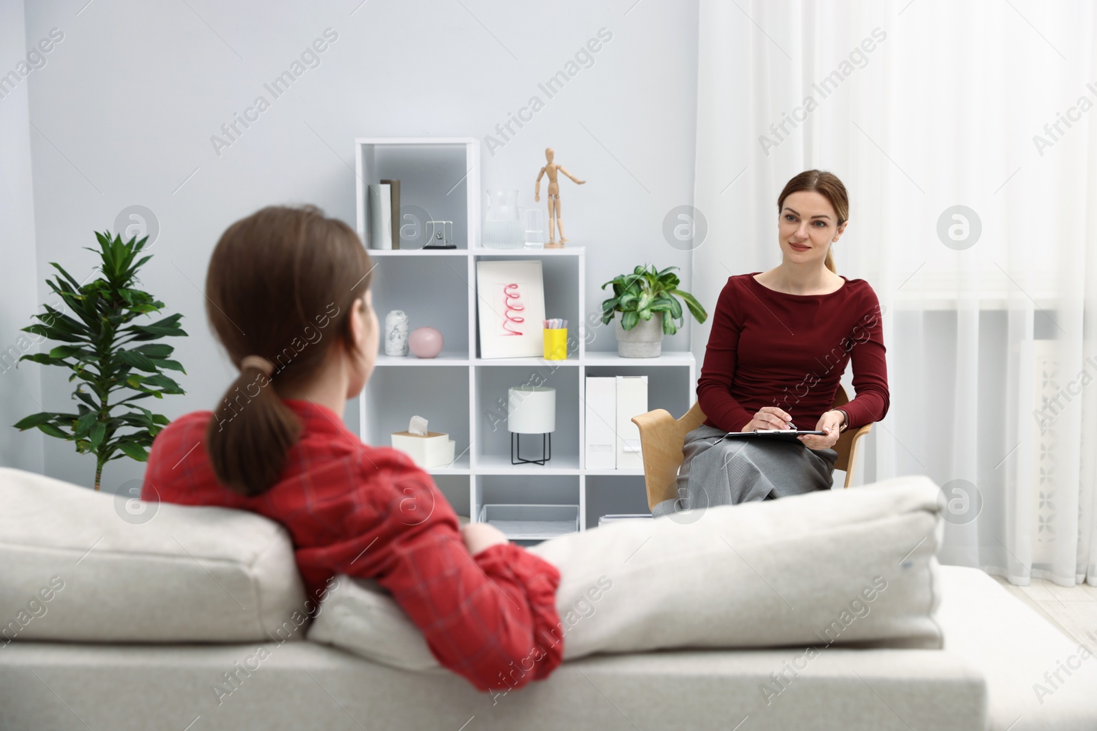 Photo of Professional psychologist working with teenage girl in office