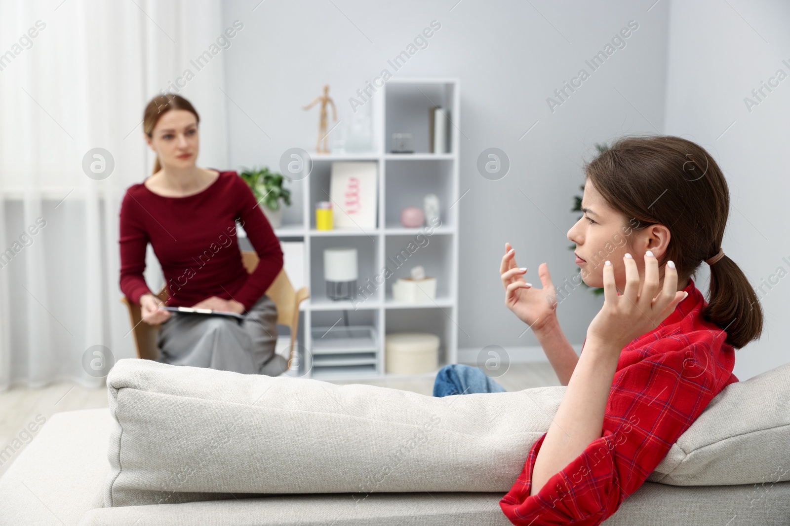 Photo of Professional psychologist working with teenage girl in office, selective focus