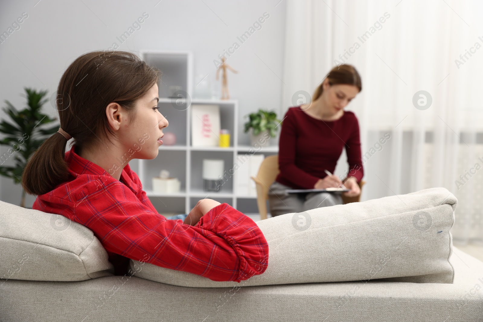 Photo of Professional psychologist working with teenage girl in office, selective focus