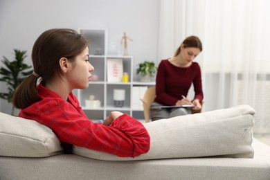 Photo of Professional psychologist working with teenage girl in office, selective focus