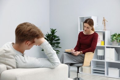 Photo of Professional psychologist working with teenage boy in office