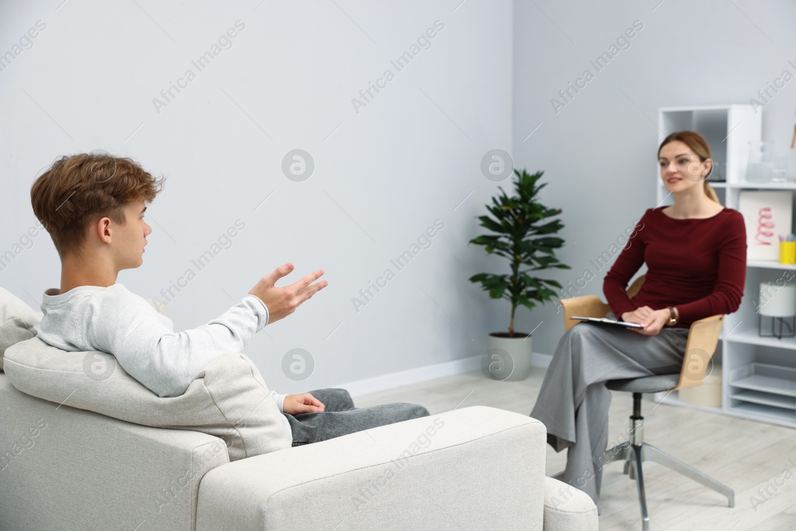 Photo of Professional psychologist working with teenage boy in office