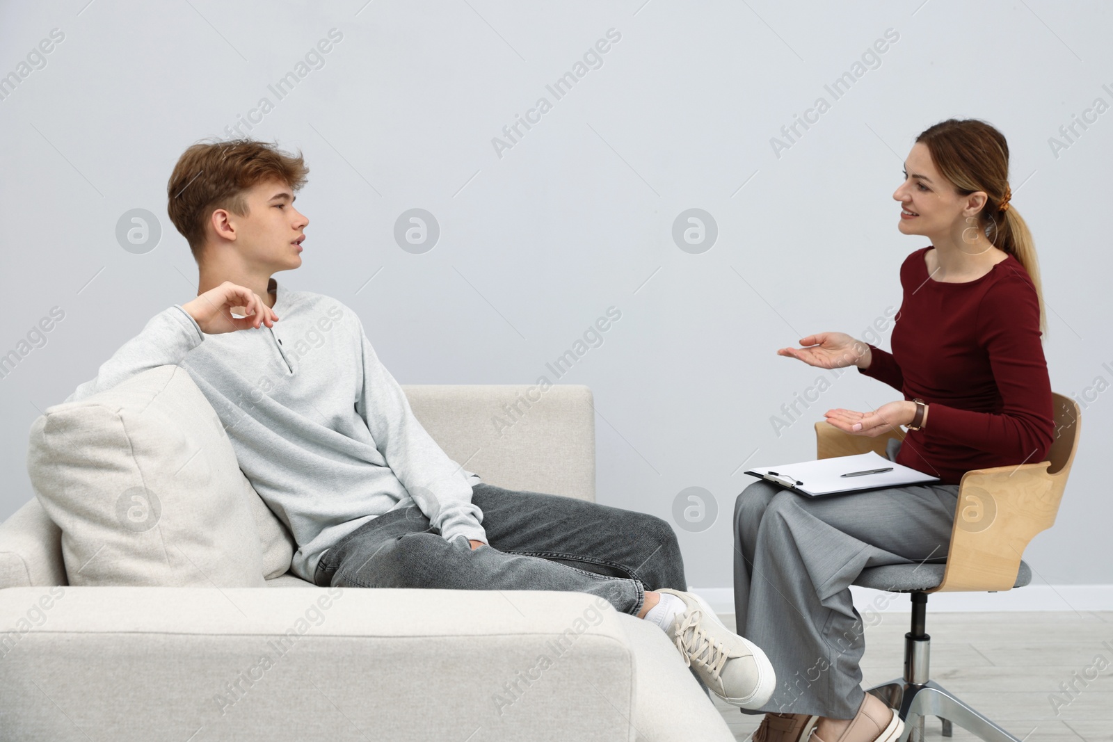 Photo of Professional psychologist working with teenage boy in office