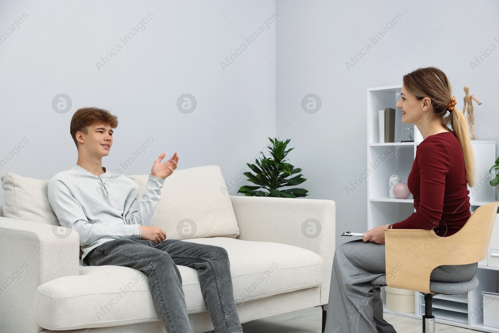 Photo of Professional psychologist working with teenage boy in office