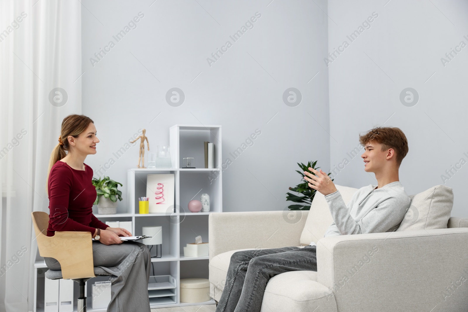 Photo of Professional psychologist working with teenage boy in office
