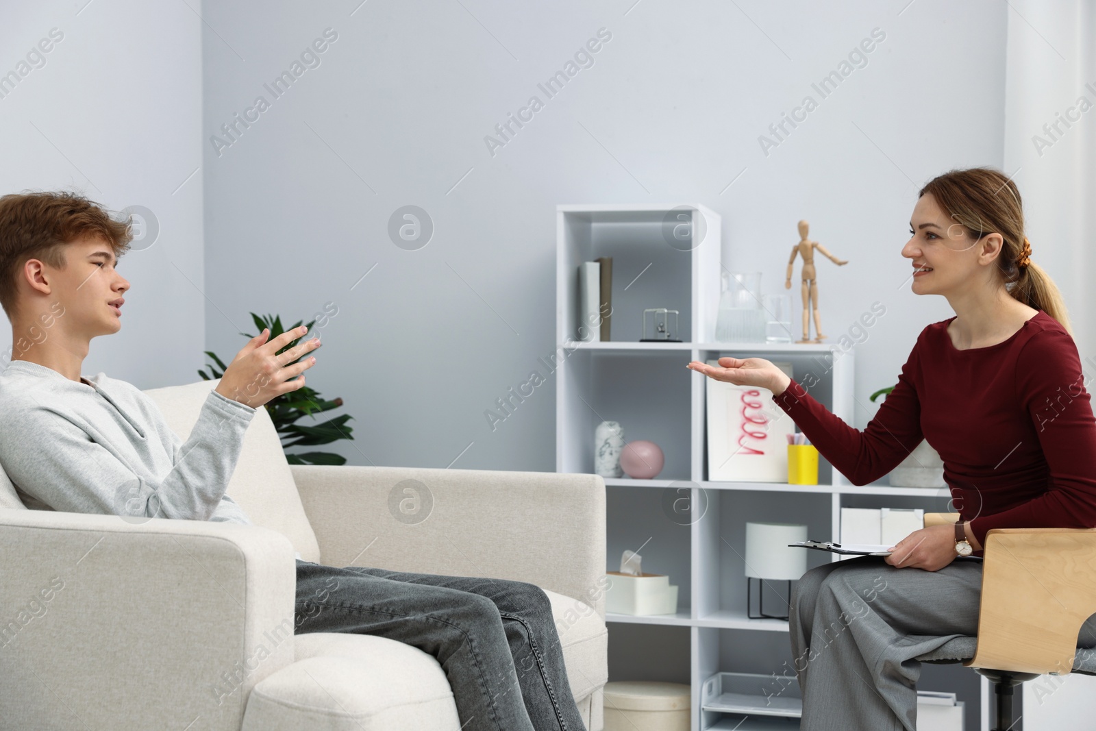 Photo of Professional psychologist working with teenage boy in office