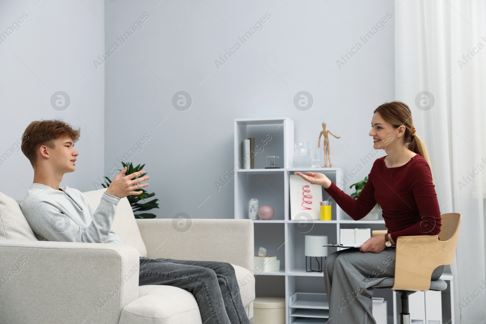 Photo of Professional psychologist working with teenage boy in office