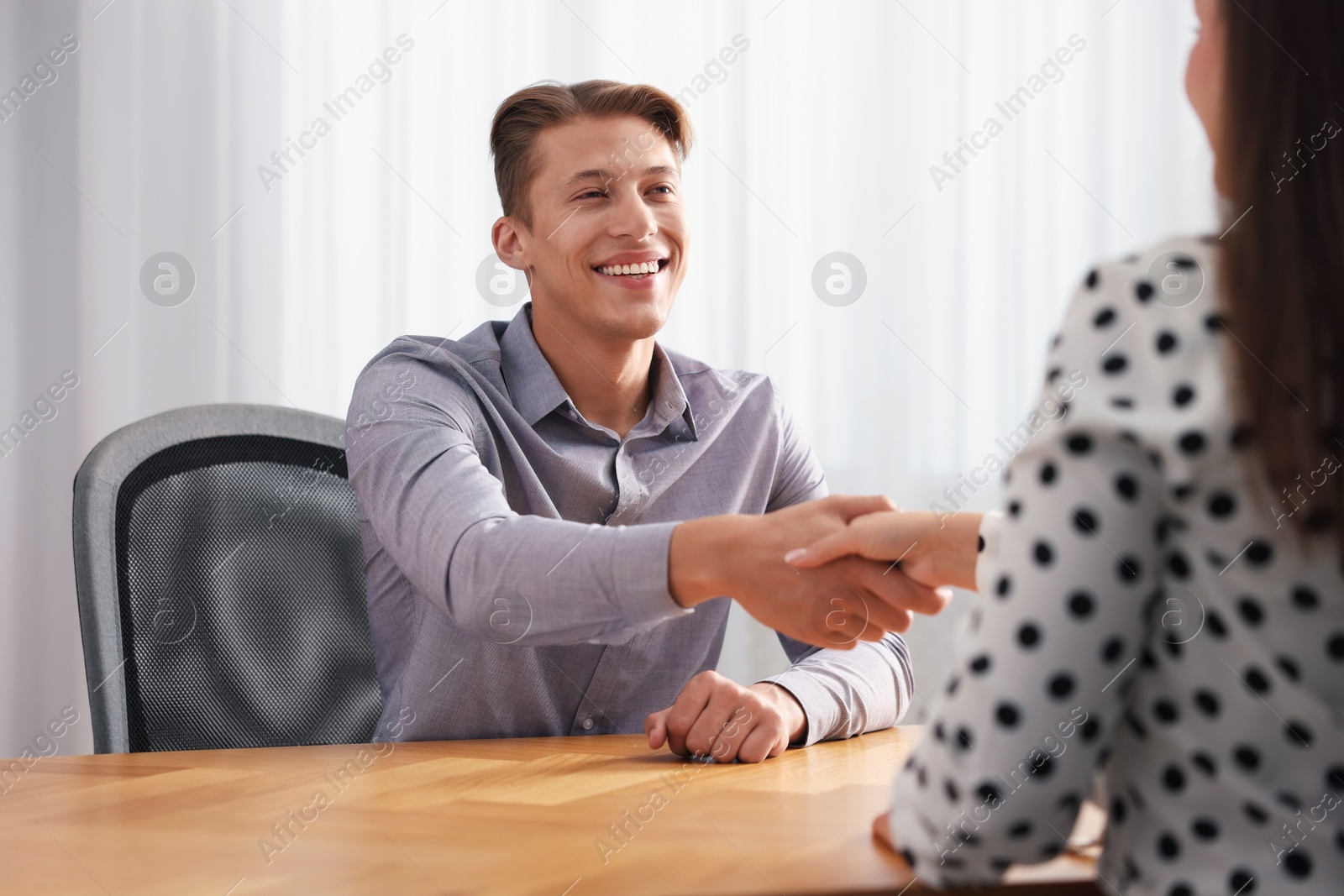 Photo of Man and woman shaking hands at wooden desk in office