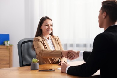 Photo of Man and woman shaking hands at wooden desk in office