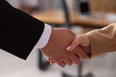 Photo of Man and woman shaking hands indoors, closeup