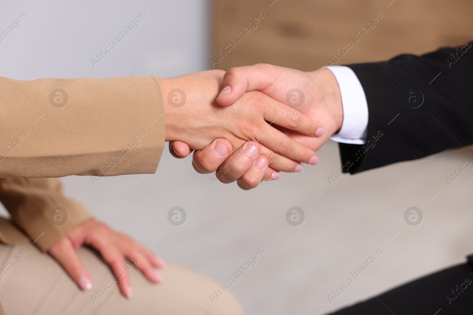 Man and woman shaking hands indoors, closeup Photo of Man and woman shaking hands indoors, closeup