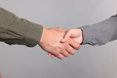 Photo of Woman and man shaking hands on light grey background, closeup