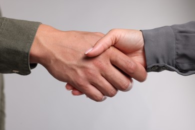 Photo of Woman and man shaking hands on light grey background, closeup